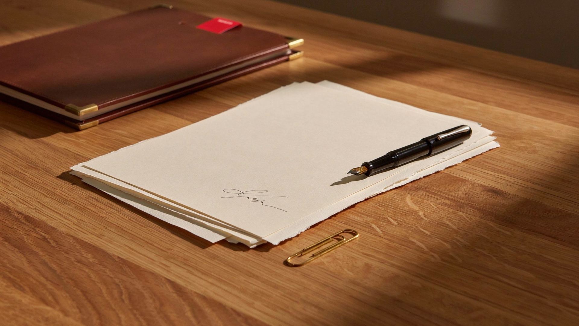 A signed suitability report and fountain pen on a warm wooden desk at the end of the day